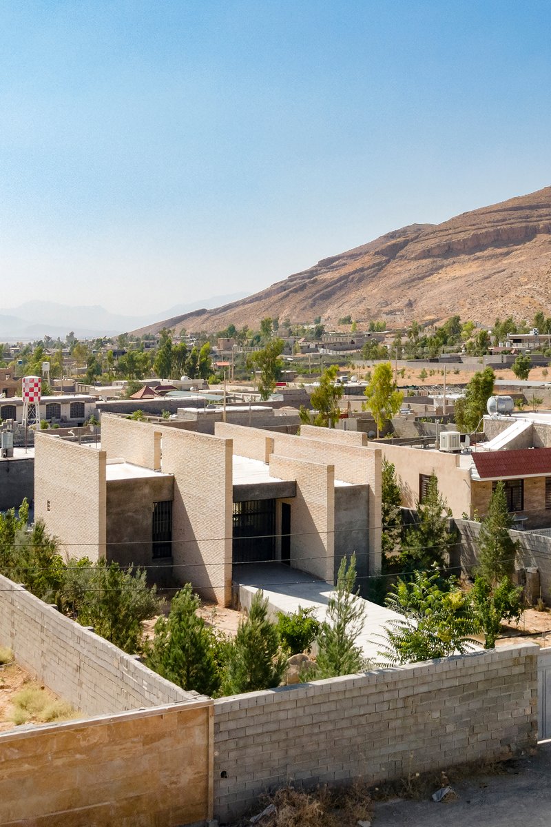 Rooftop view of the residence set against a hillside neighborhood with young trees in foreground