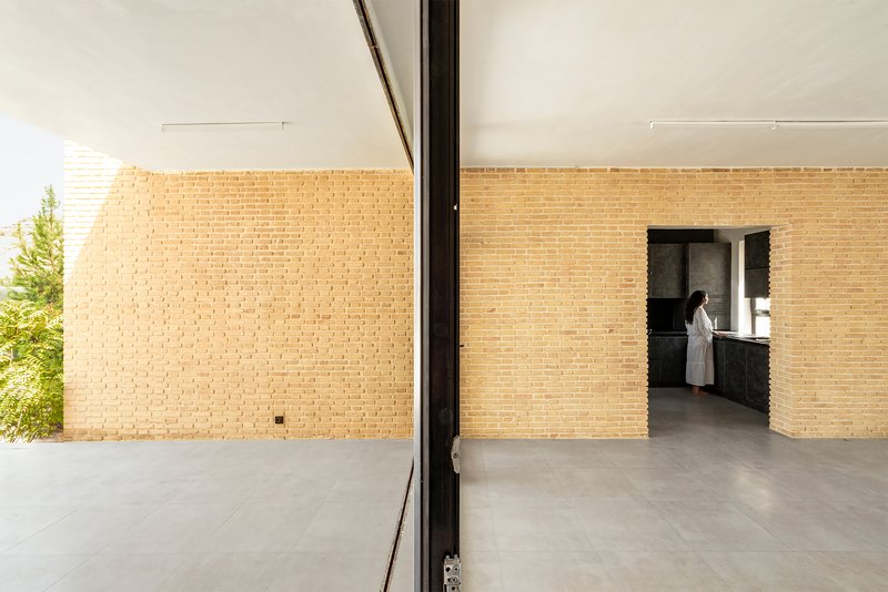 View through sliding glass door to brick-walled courtyard with plantings visible beyond the corner opening
