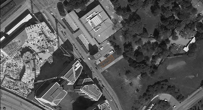 Aerial site view showing the café’s urban edge beside open green space.