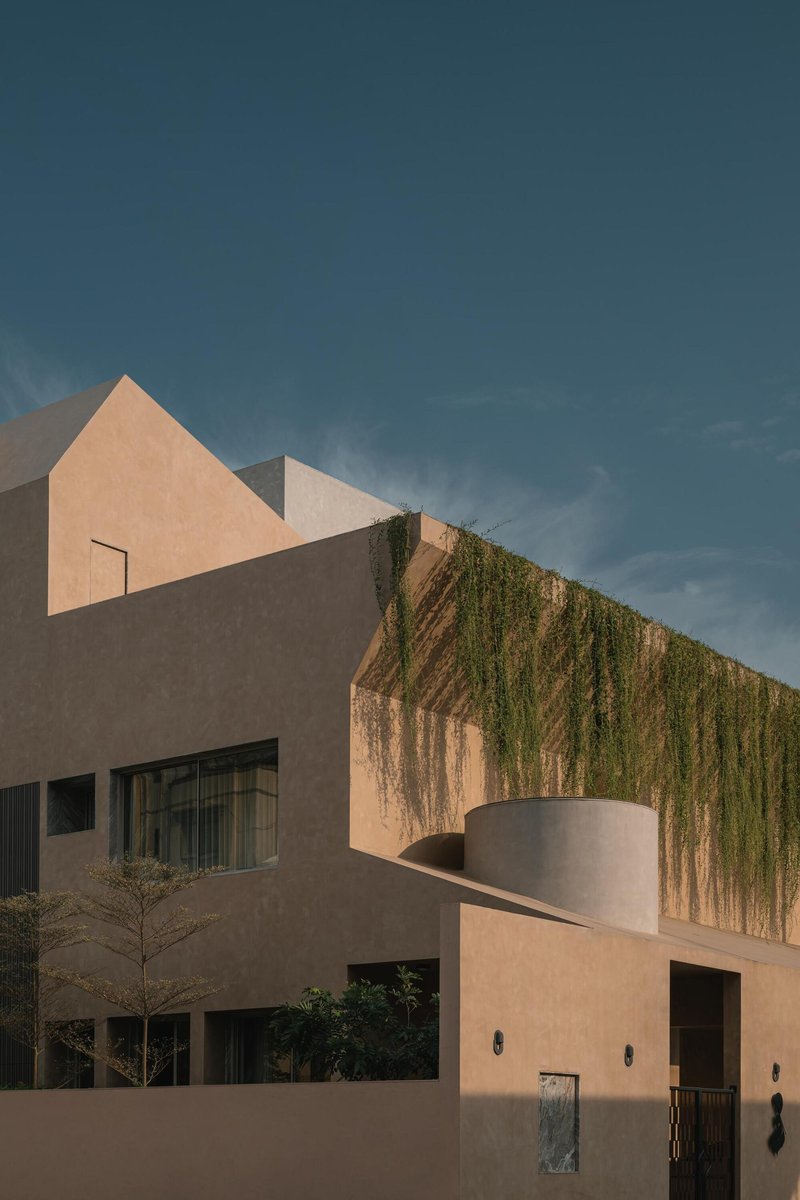 Facade detail featuring planted upper terrace with trailing vegetation above a cylindrical cantilevered element