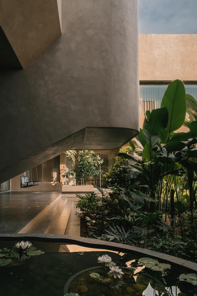 Concrete cylindrical column beside a reflecting pool with water lilies and tropical planting