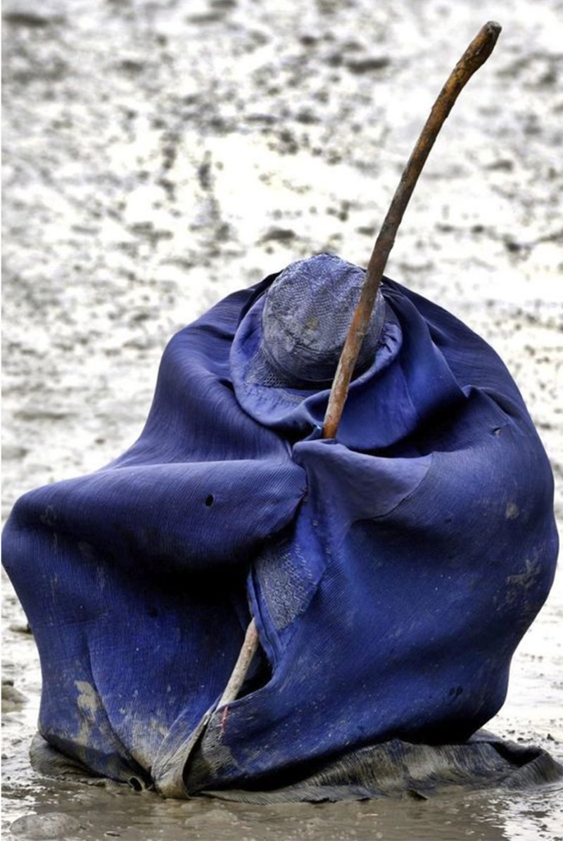 A blue cloak captures hardship, endurance, and silent resilience.