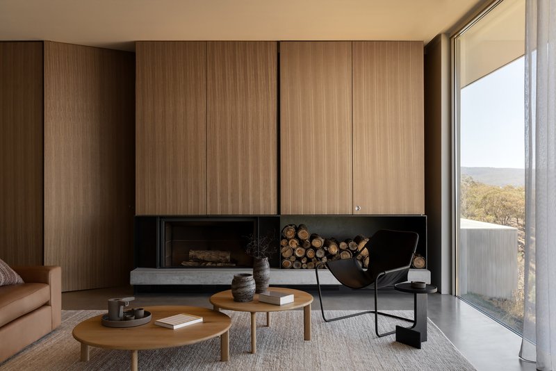 Living room with timber-clad fireplace wall and stacked firewood beneath upper cabinetry