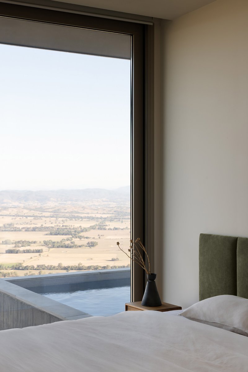 Bedroom window framing a hazy valley view with a tiled pool edge visible outside