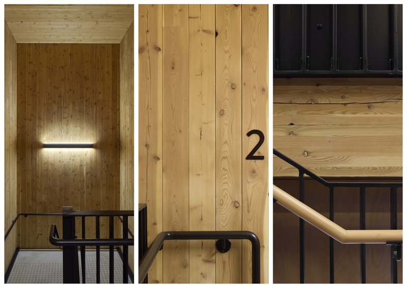 Timber-clad stairwell with black metal railing and wall-mounted linear light fixture illuminating vertical paneling