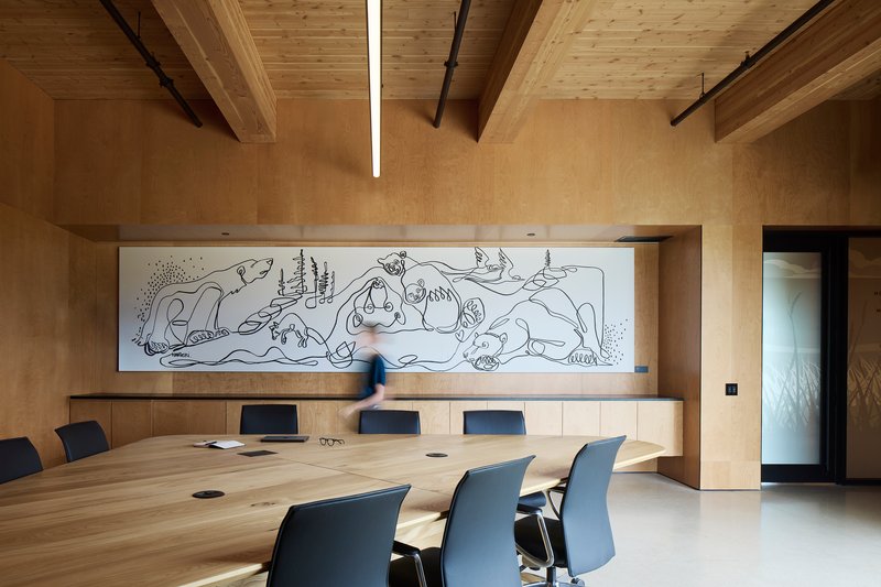 Conference room with long timber table and wall mural under exposed beam ceiling with linear lighting