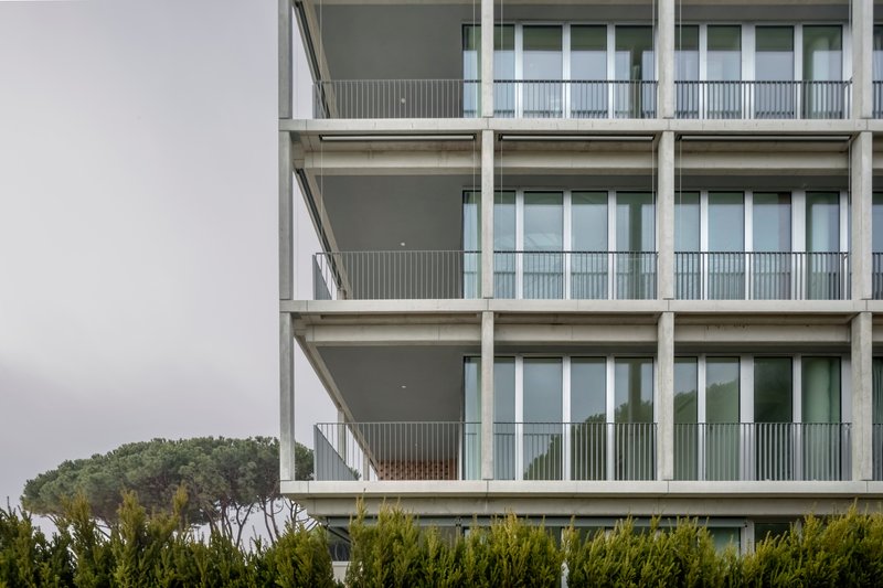 Detail of stacked balconies with metal railings, deep overhangs and glass doors on an overcast day