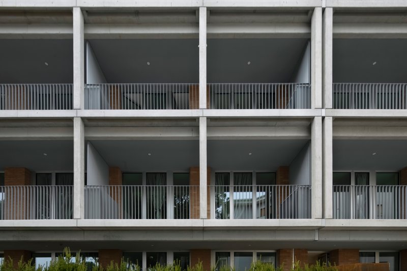Concrete structural grid facade with recessed balconies lined with vertical timber slats and metal railings