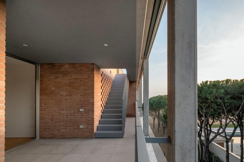 Covered terrace with exposed brick walls and a concrete staircase leading to the upper level