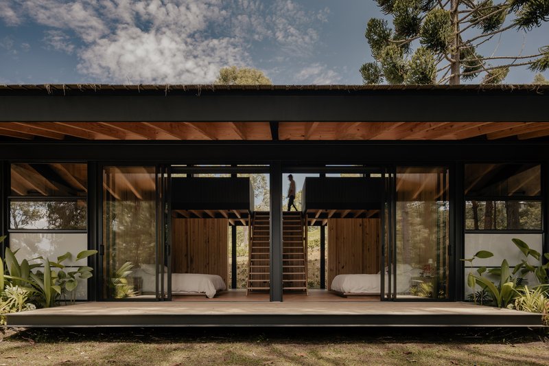 Front elevation showing sliding glass doors and central staircase beneath exposed timber ceiling beams and black steel frame