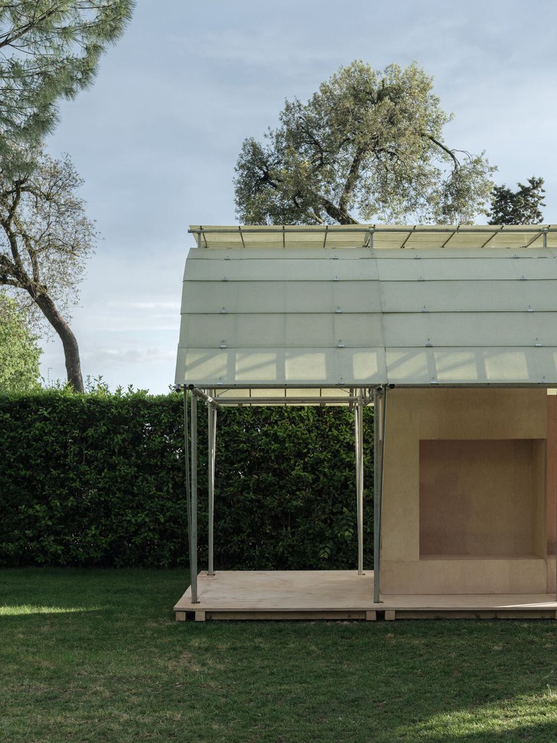 Side view of the pavilion showing timber deck, diagonal steel supports, and plywood enclosed volume