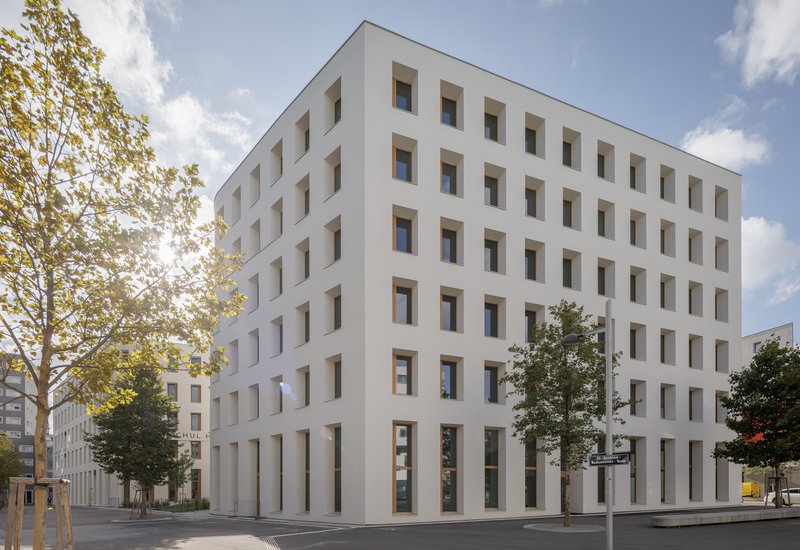 Corner view of the white facade with timber-framed windows and tall ground-floor columns
