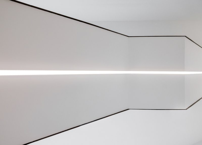 Close-up of a coved ceiling corner with continuous linear lighting and thin metal edge trim