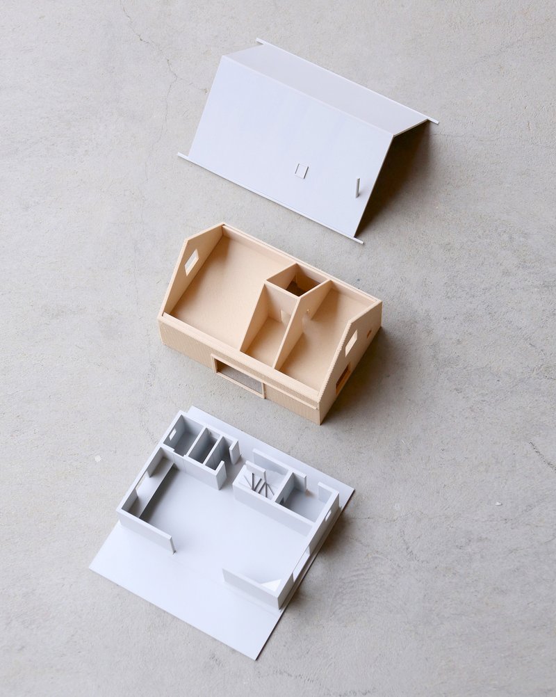 Three physical models in white and beige card stock showing the house with removable roof piece