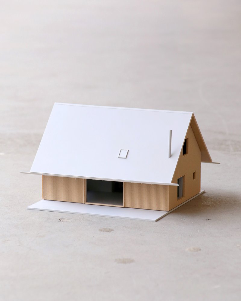 Physical model of the house with gabled roof, vertical timber cladding, and central glazed opening