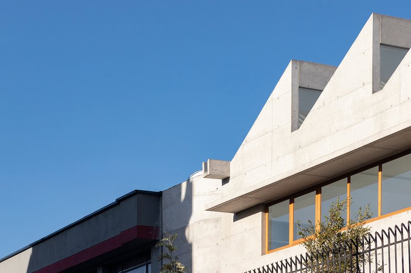 Detail of stepped concrete roofline and cantilevered overhang with timber framed glazing below