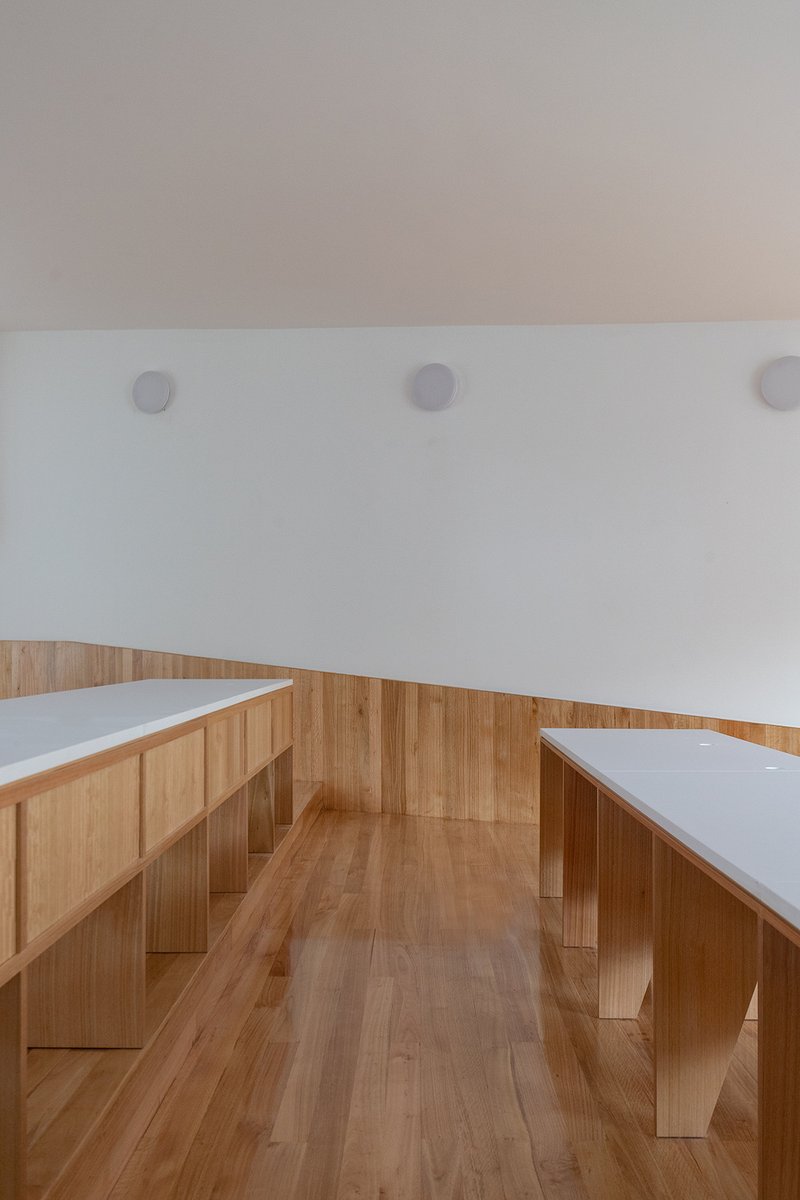 Reading alcove with timber benches and built-in seating facing white upper walls in daylight