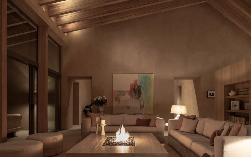 Living room with exposed timber ceiling and central fire table illuminated by evening lamplight