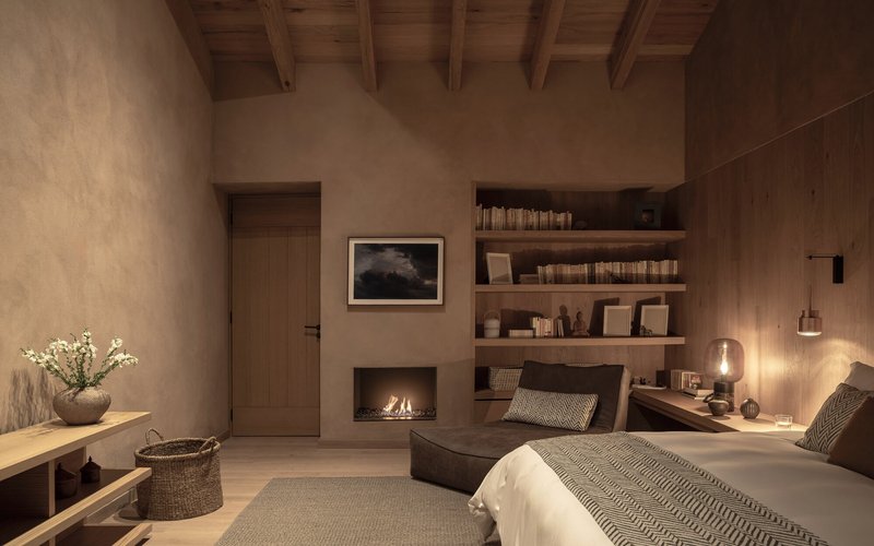 Bedroom view at dusk with fireplace flickering beside timber-clad wall and open shelving