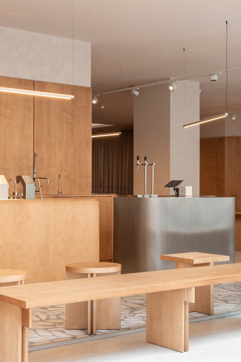 Interior counter area with light wood joinery and brushed metal surfaces under suspended track lighting
