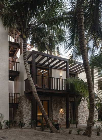 This architectural image showcases a multi-story building with a tropical design, featuring a stone 