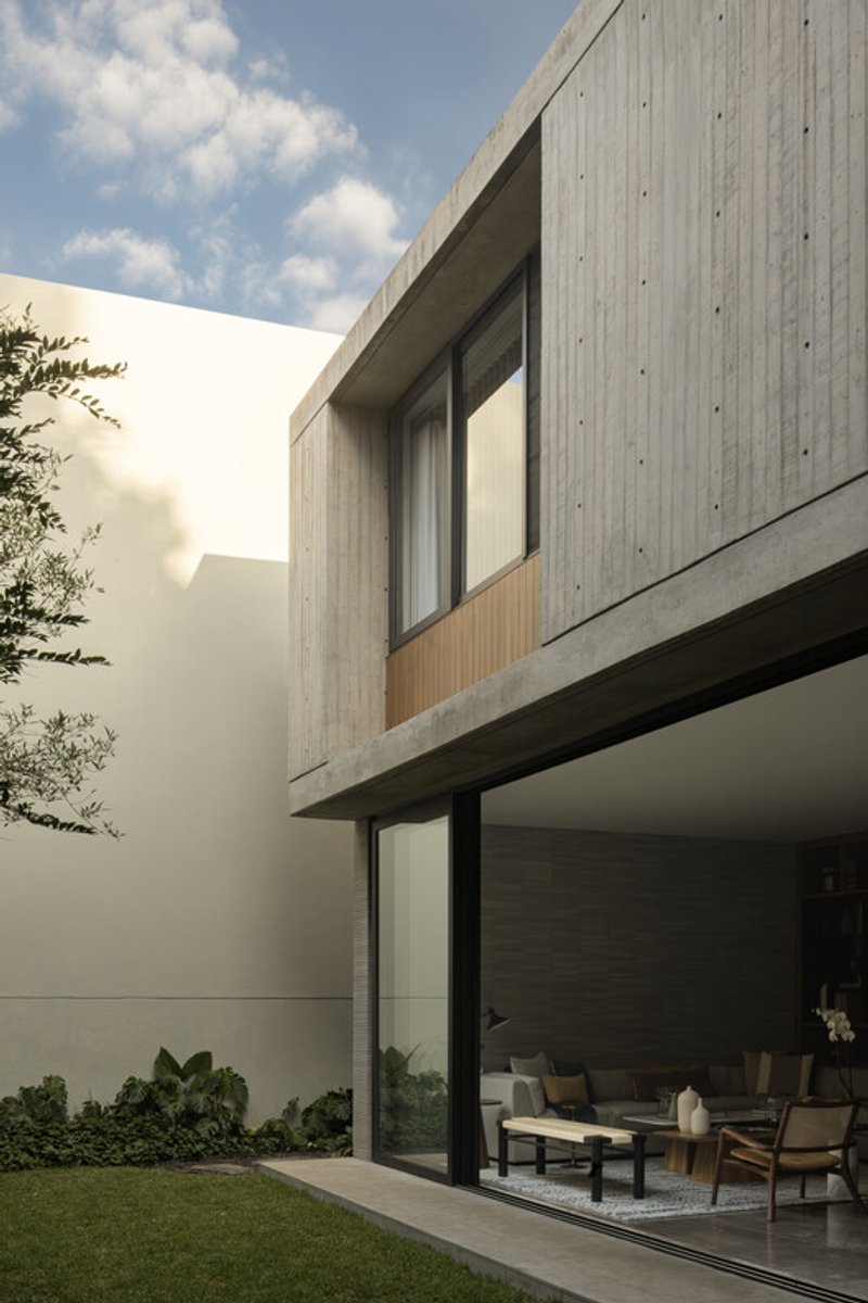 Courtyard view of the concrete and timber upper volume cantilevering over floor-to-ceiling glazing below