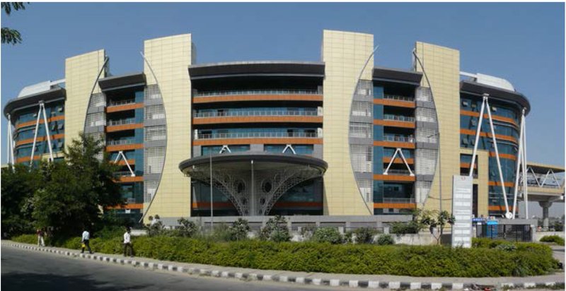 Street view of the curved facade with vertical fins and horizontal sunshading under clear sky