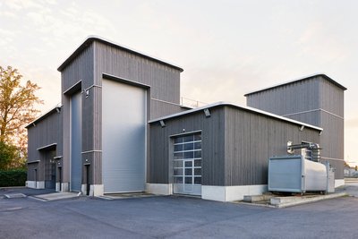 This architectural image showcases a modern industrial building with a corrugated metal facade. The 