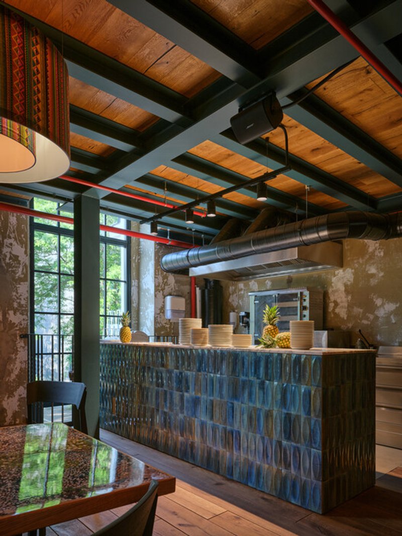 Reception desk with blue ceramic tile front beneath exposed timber ceiling and ductwork