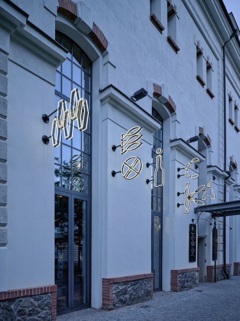 Street facade with neon food symbols mounted on white plaster at dusk