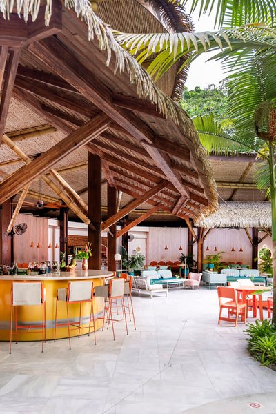 This architectural image showcases a tropical open-air bar and lounge area, featuring a thatched roo