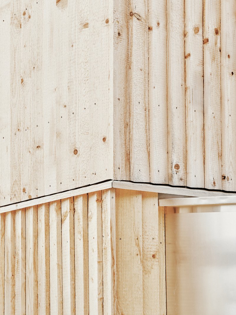 Close-up of an external corner showing two layers of vertical timber boarding