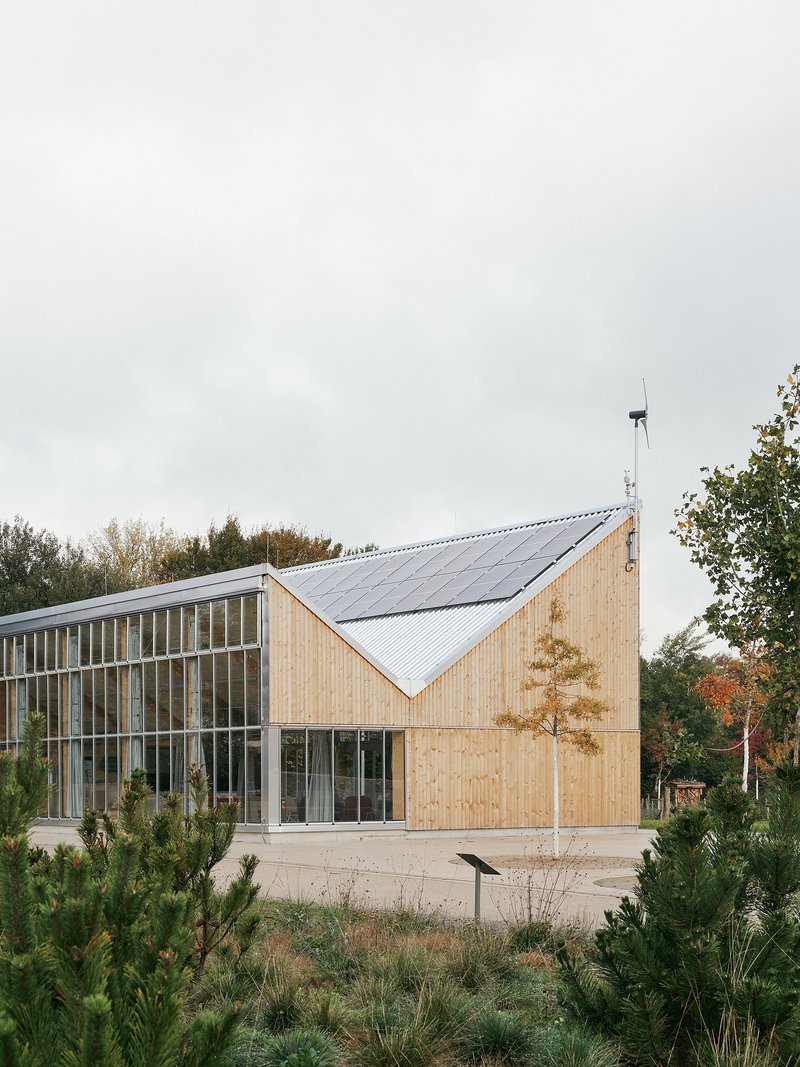 Asymmetric pitched timber pavilion with rooftop solar panels and a small wind turbine