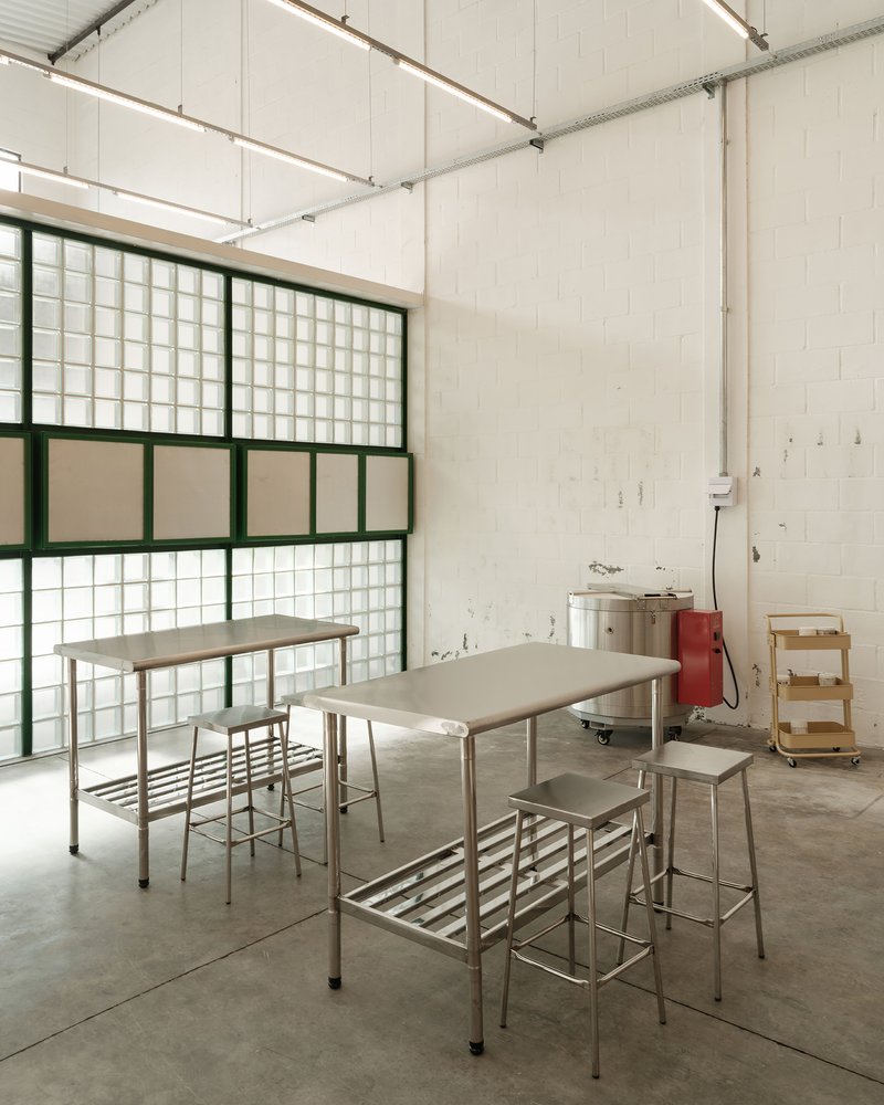 Workspace with metal tables and stools beneath glass block window wall in polished concrete floor