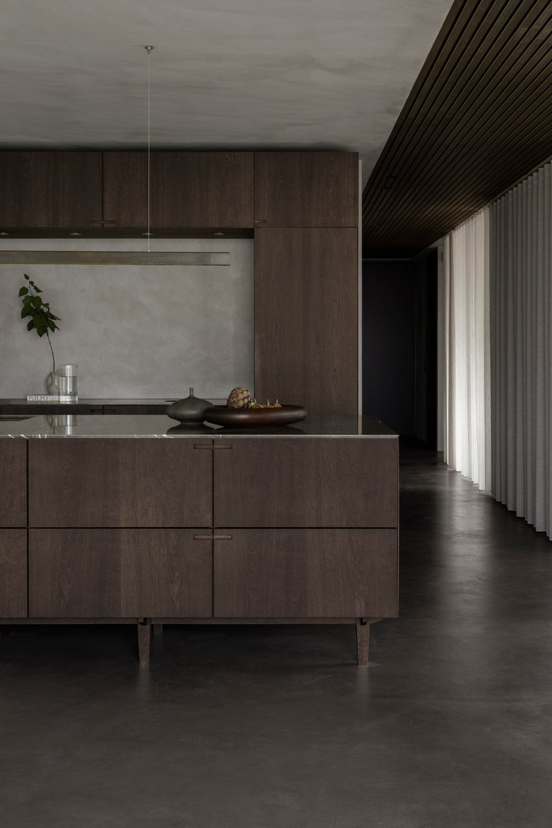Kitchen island with timber cabinetry beneath a slatted timber ceiling and floor-length curtain