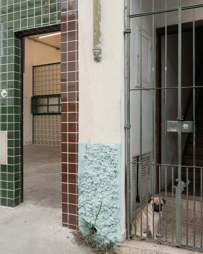 Doorway flanked by green and brown tile pilasters with translucent glass block partition and metal gate visible