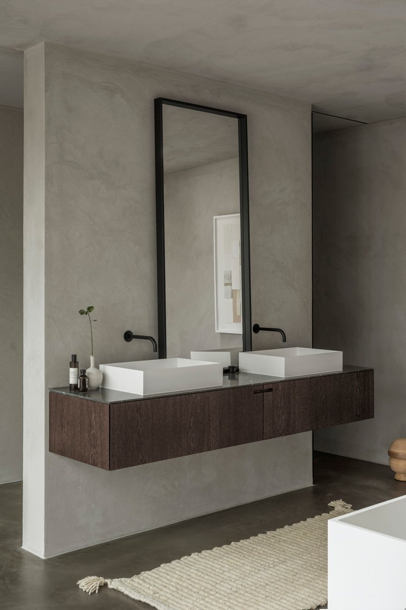 Double vanity with white rectangular basins on dark wood cabinetry against grey plaster walls