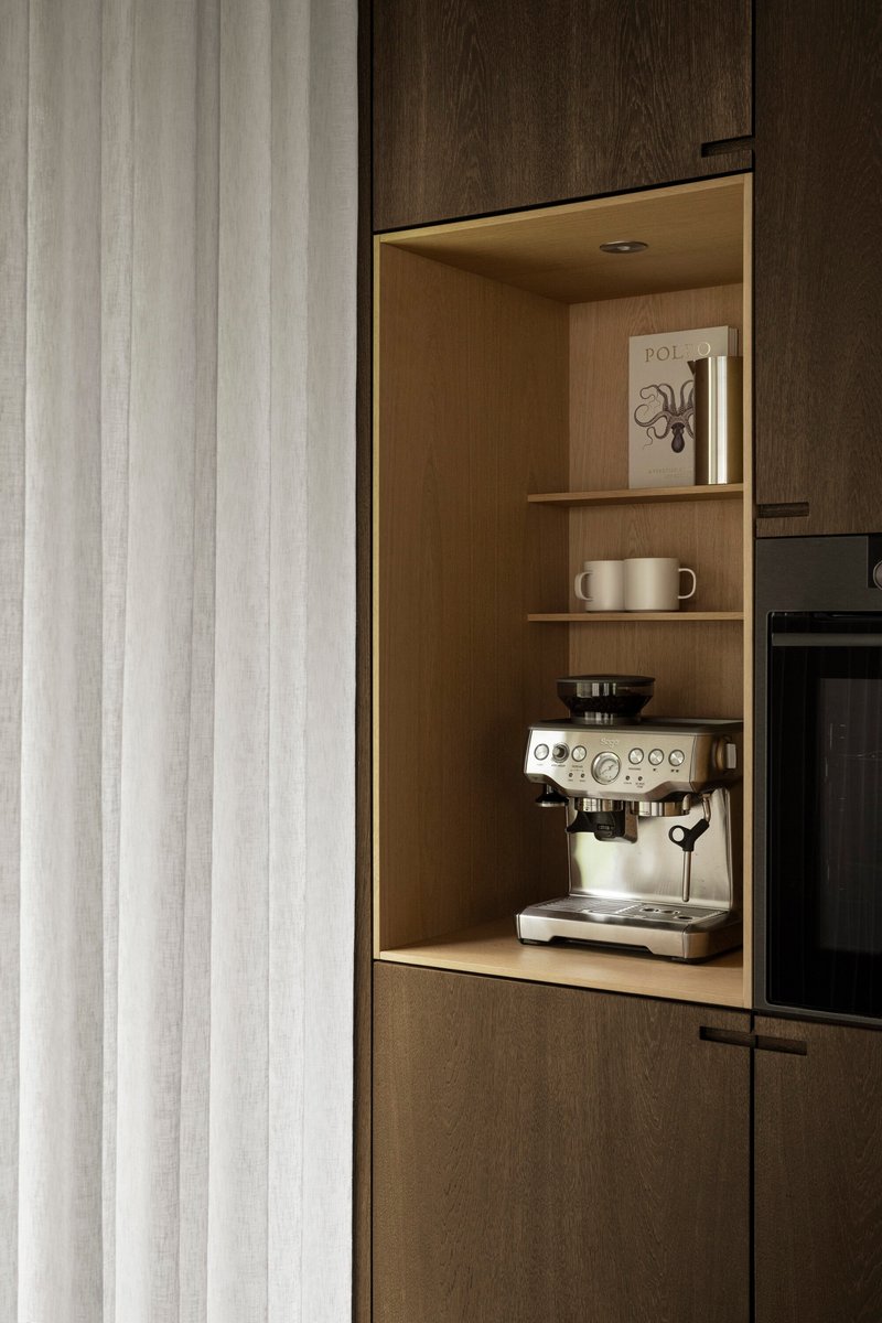 Illuminated timber niche with espresso machine and shelving recessed into dark wood cabinetry