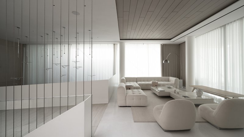 Open living room with pendant light grid, white sectional seating, and floor-to-ceiling sheer curtains