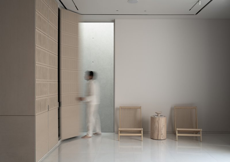 Entryway with fluted wall paneling and a blurred figure passing through the doorway