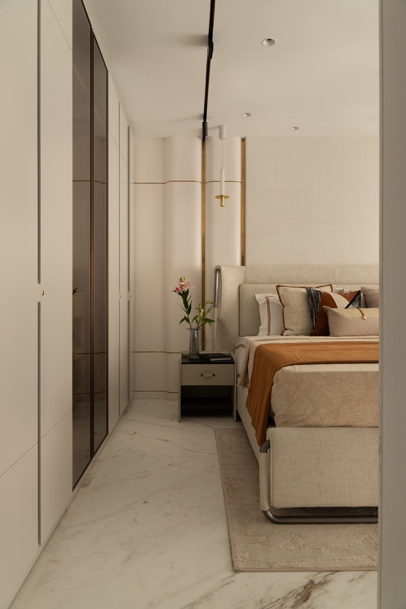The dressing corridor: floor-to-ceiling mirrored wardrobes face a curved fluted feature wall in cream and brass.