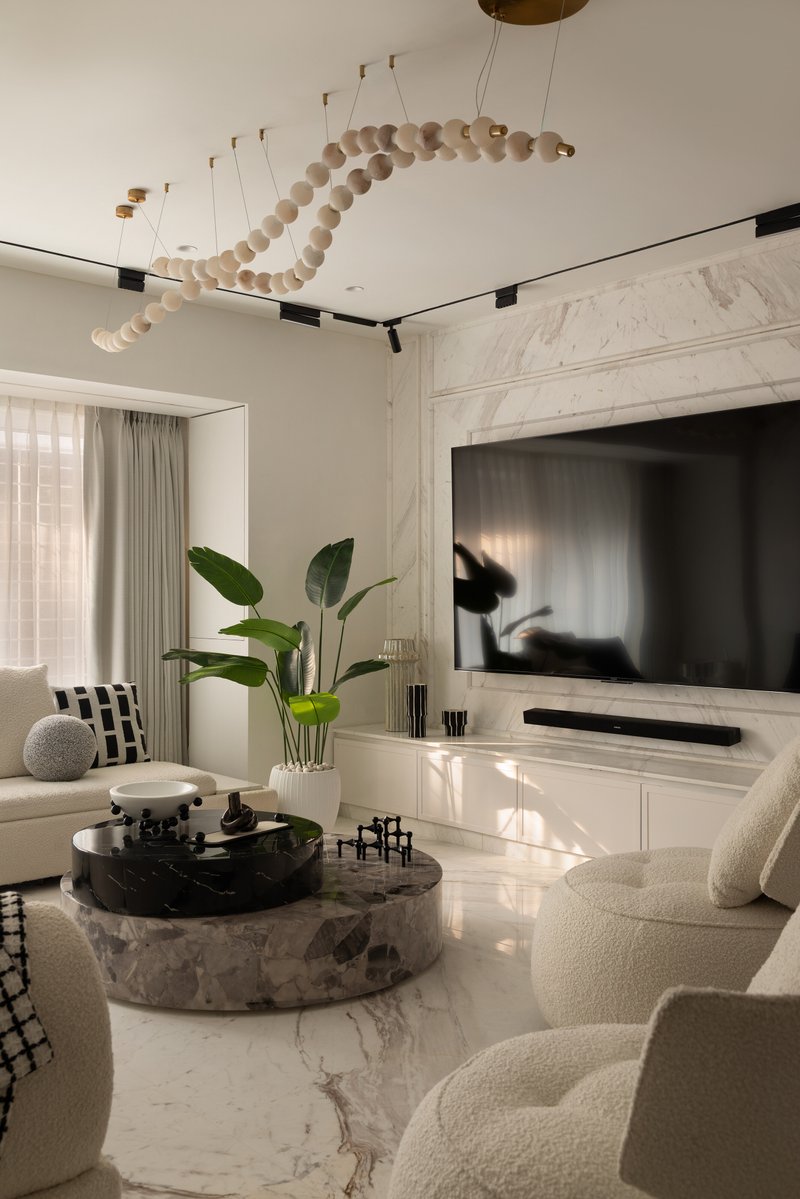 The living room, anchored by a marble-clad feature wall and a custom beaded ceiling installation.
