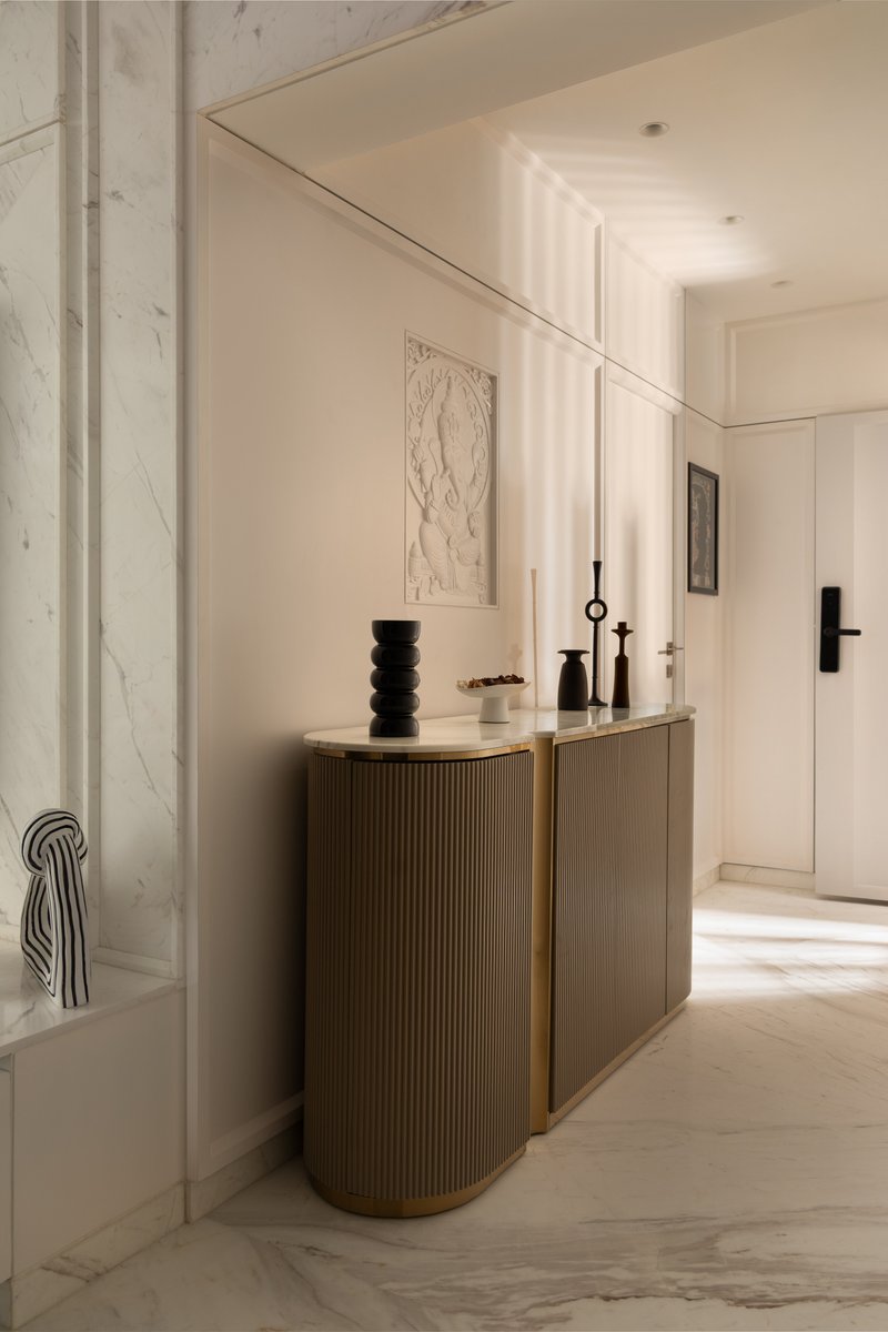 The foyer console: a fluted brass-banded cabinet with a carved Ganesh relief above.