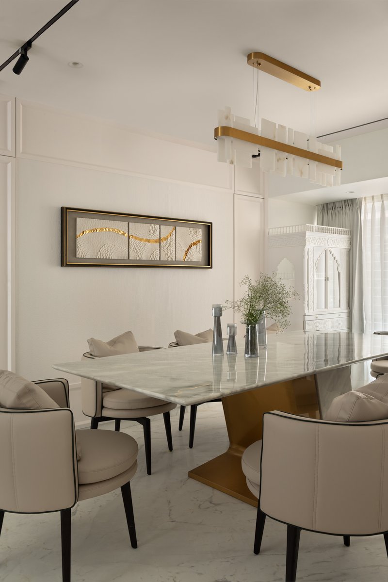 The custom alabaster-and-brass pendant above the dining table, with the gold-leaf triptych beyond.