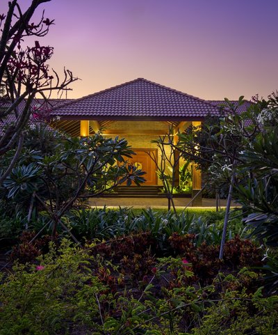 This architectural image showcases a tropical-style building at twilight, featuring a tiled roof, br