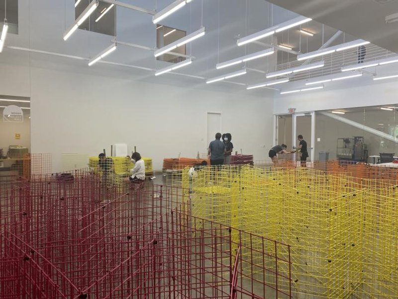 The modular panels with pink, orange, and yellow coatings were partially assembled inside the arts center before being moved to the front of the building. (Photo courtesy of Moody Center for the Arts)