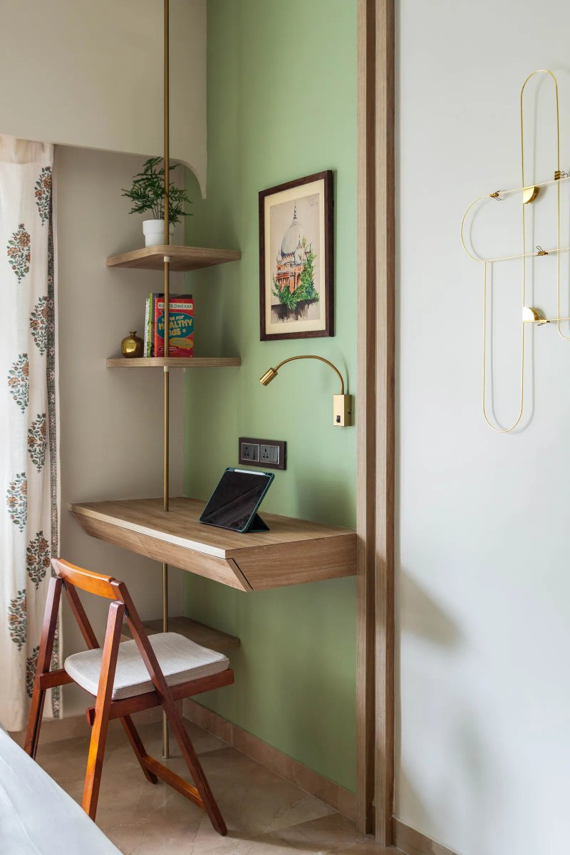 The study unit in the primary bedroom has shelves attached to a long brass rod. The metallic detail finds continuity in the wardrobe handles, knobs and wall hangings.  Anuja Kambli