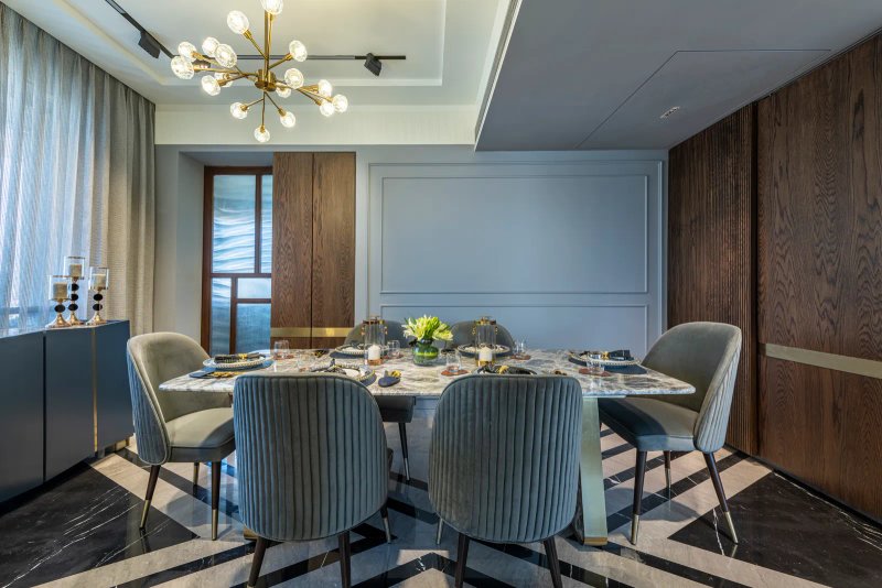 In the dining room, an elongated stone table takes centre stage, while ribbed chairs add a tactile touch. A gilded chandelier gives the room a glam spin.  PRASHANT BHAT