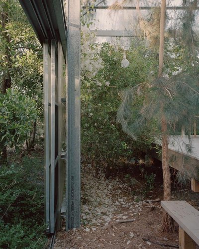 This architectural image showcases a greenhouse structure integrated into a lush garden setting. The