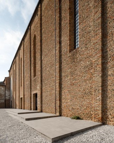 This architectural image showcases a brick building facade with a series of arched openings and a pr